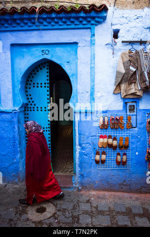 Chefchaouen, Marokko: Eine Frau geht über einen traditionellen hölzernen Tür im Blau getünchte Medina, Altstadt. Stockfoto