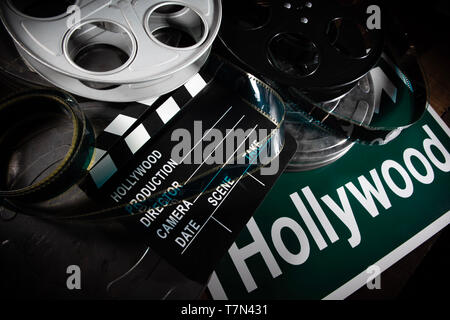 Mehrere Filmrollen und Schindeln auf einem hölzernen Hintergrund. Film, Hollywood, Unterhaltung Industrie Objekte Stockfoto