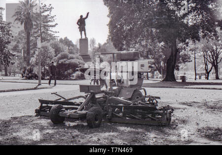 1977 Sydney, Australien: Ein 1970er motorisierte Rasenmäher sitzt auf einem Rasen Platz in Sydney's zentral gelegene Hyde Park unbeaufsichtigt. Im Hintergrund die Menschen entlang der asphaltierten Pfaden wandeln und die Statue von Captain Cook steht gegen einen klaren Himmel. Stockfoto