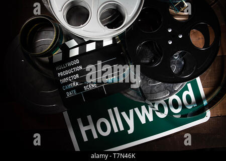 Mehrere Filmrollen und Schindeln auf einem hölzernen Hintergrund. Film, Hollywood, Unterhaltung Industrie Objekte Stockfoto