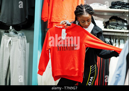 Afican amerikanische Frauen in Trainingsanzügen einkaufen bei Sportswear Mall gegen Regale mit Sweatshirt. Sport store Thema. Stockfoto