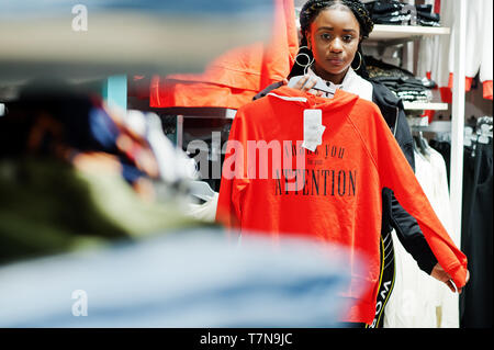 Afican amerikanische Frauen in Trainingsanzügen einkaufen bei Sportswear Mall gegen Regale mit Sweatshirt. Sport store Thema. Stockfoto