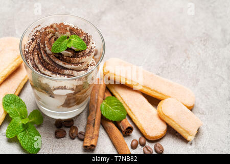 Classic Tiramisu Dessert im Glas und savoiardi Cookies auf konkreten Hintergrund Stockfoto