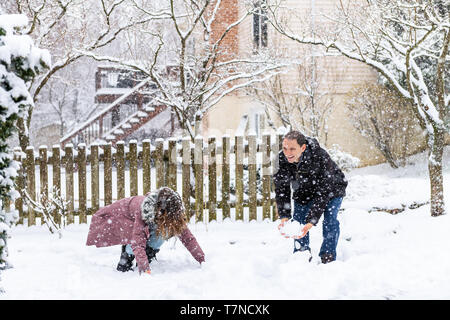 Junger Mann Frau Paar spielen, Schneebälle im Winter Schneesturm im Haus Garten Vorgarten schneit mit Bäumen im Schnee glücklich Stockfoto