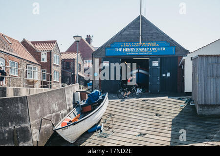 Sheringham, Großbritannien - 21 April, 2019: Frau Zyklen vor der Henry Ramey Upcher, Fisherman's Heritage Centre in Sheringham, ein englischer Seaside abschleppen Stockfoto