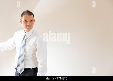 Junger Mann Geschäftsmann in Business Hemd Krawatte stehend durch die Wand im Zimmer mit futuristischen Konzept Licht Stockfoto