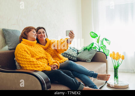 Ältere Mutter und ihrer Tochter, die sie zu Hause verwenden selfie Smartphone. Muttertag Konzept. Stockfoto