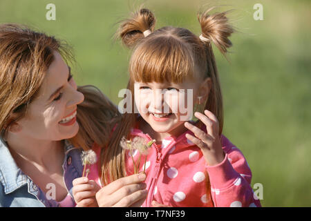 Mutter und Tochter mit Löwenzahn in Park Stockfoto