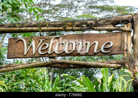 Text Willkommen auf einer Holzplatte in einem Regenwald Dschungel der tropischen Insel Bali, Indonesien. Holzschild Inschrift in den asiatischen Tropen willkommen, in der Nähe Stockfoto