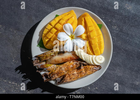 Im thailändischen Stil Dessert, gelbe Mango mit Banane klebriger Reis in Palmblättern. Gelbe Mango und klebriger Reis ist beliebt traditionelle Speisen von Thailand. Schließen u Stockfoto