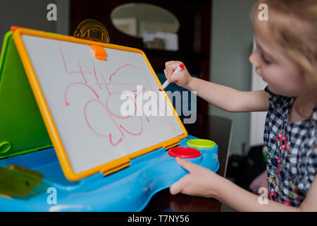 Ein vier Jahre altes Mädchen übt ihre Handschrift auf einem Whiteboard Stockfoto