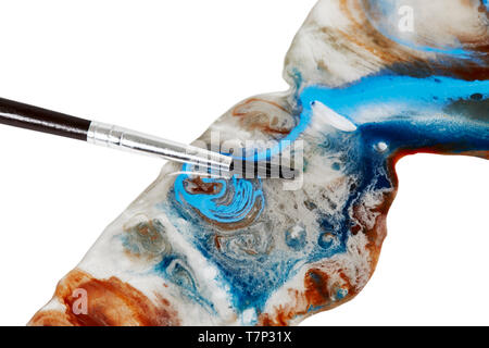 In der Nähe von Blue und tan Farbe verschüttet mit einem kleinen Künstler Pinsel isoliert auf weißem Stockfoto