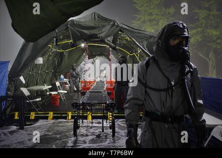 Soldaten aus 181St Chemical Company (Hazard Response), Task Force Ops, Joint Task Force zivilen Unterstützung (JTFCS), sind bereit, für Rollenspieler durch ihre Masse Unfallversicherung Dekontamination Linie an Übung Guardian Antwort bei muscatatuck Urban Training Center, 4. Mai 2019 zu kommen. Wenn gerichtet, JTFCS bietet das Kommando und die Kontrolle der 5.200-person Verteidigung chemische biologische, radiologische nuklearen (CBRN) Response Force (DCRF) während eines katastrophalen Krise zur Unterstützung der zivilen Behörden und die Leitung der Föderalen Agentur. Lebendige Reaktion/Guardian Reaktion ist eine jährliche, kombinierte Kommandostellenübung ein Stockfoto