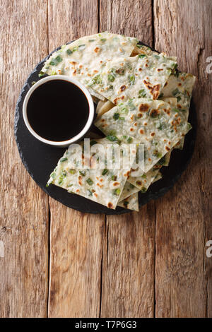 Vegan Schalotten Pfannkuchen sind eine knusprig gebratene Chinesische Fladenbrot close-up auf einem Brett auf den Tisch. Vertikal oben Ansicht von oben Stockfoto