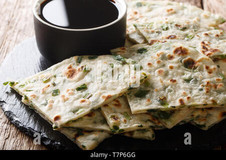 Chinesische Vorspeise gebratene Schalotten Pfannkuchen mit Sauce in der Nähe serviert auf einem Board auf einem Tisch. Horizontale Stockfoto