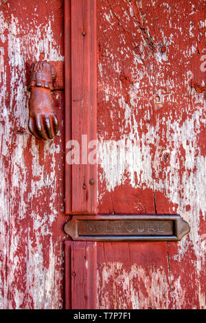 Klopfer und eine Mailbox im Namen 'Mr Le curé' auf einer hölzernen Tür mit abblätternde Farbe, Frankreich. Stockfoto