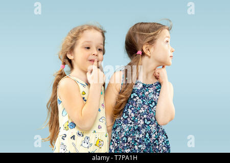 Wunderschöne emotionale kleine Mädchen auf blauem Hintergrund isoliert. Halbe Länge Portrait von Happy Schwestern oder Freunde tragen Kleider und Spielen. Konzept der Gesichtsausdruck, die menschliche Emotionen, Kindheit. Stockfoto