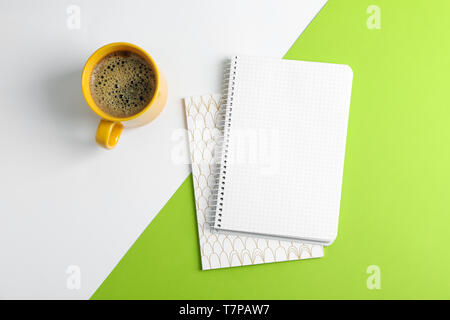 Tasse Kaffee mit Copybooks auf farbigen Hintergrund, Ansicht von oben Stockfoto