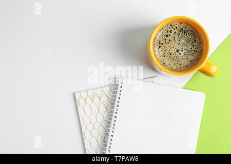 Tasse Kaffee mit Copybooks auf farbigen Hintergrund, Ansicht von oben Stockfoto