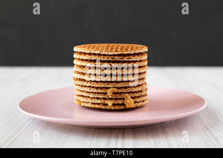 Stapel von hausgemachten Niederländische stroopwafels mit Honig - Karamell Füllung auf eine rosa Platte, Seitenansicht. Stockfoto