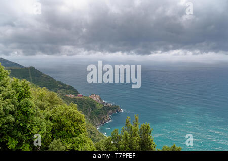 Auf einem weit entfernten Manarola von hoch oben auf die Cinque Terre trail als graue Wolken über dem Meer Rollen Stockfoto