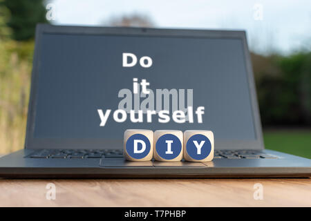 Würfel bilden die Abkürzung 'DIY'. Würfel auf einem Notebook. Der Text 'Do it Yourself' auf dem Display geschrieben werden. Stockfoto