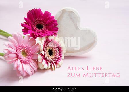 Rosa Blumen und einer weiß lackierten Holz- Herzen auf einer pastellfarbenen Hintergrund, deutsche Text Alles Liebe zum Muttertag, d. h. Alles Liebe zum Muttertag Stockfoto