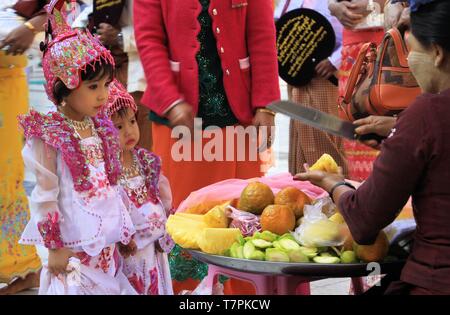 MANDALAY, MYANMAR - Dezember 18. 2015: Cute burmesischen Mädchen Wahl Früchte während der Zeremonie an Maha Muni Pagode Stockfoto