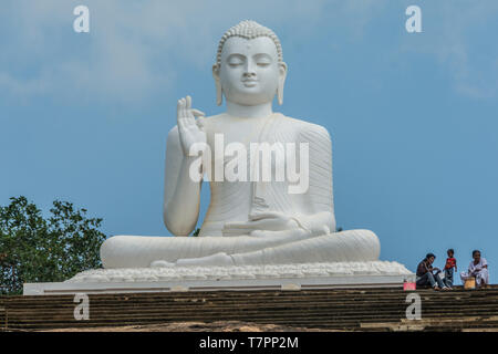 Große sitzende Statue des Buddha an der Spitze eines kleinen Hügels, Mihintale, Sri Lanka. Stockfoto