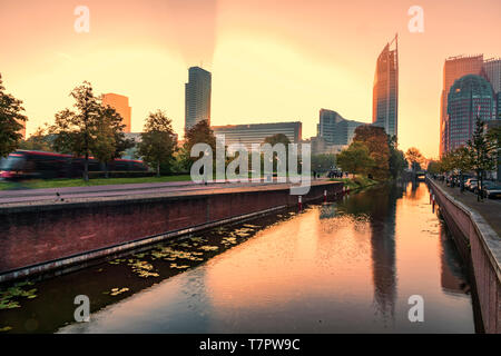 Sonnenaufgang über Den Haag Skyline mit einer kräftigen Farbe orange Casting hash Lichter durch die Gebäude Reflexion auf dem Wasser des ruhigen Kanal Stockfoto