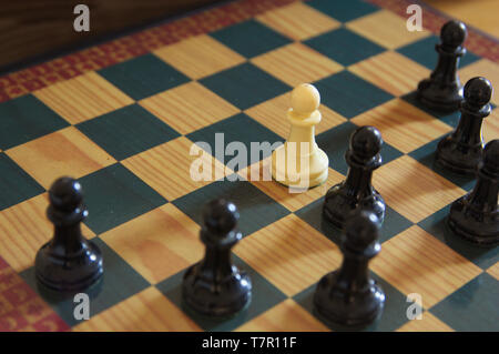 Schwarz schach Schachfiguren Surround ein weißer Bauer auf dem Schachbrett isoliert Stockfoto
