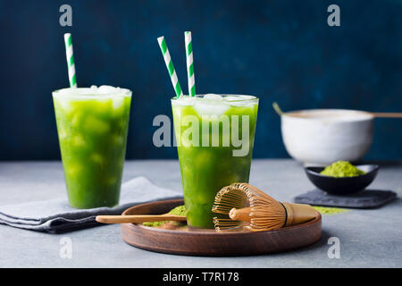 Matcha, grüner Tee Eis Tee, Cocktail im hohen Glas auf Holzplatte. Grauen Stein Hintergrund. Stockfoto