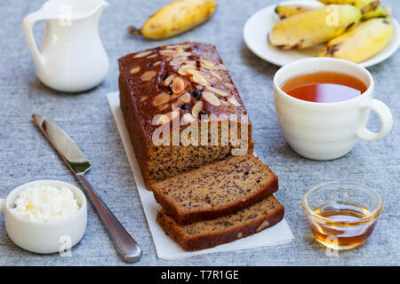 Banane Kuchen, Brot Brot mit Schokolade und Tee auf grau Background. Stockfoto