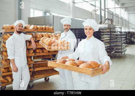 Bäcker halten Sie ein Tablett mit frischem Brot in der Bäckerei. Stockfoto