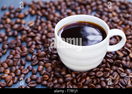 Schwarzer Kaffee in weisser Schale auf frisch gerösteten Kaffeebohnen Hintergrund. Close Up. Stockfoto