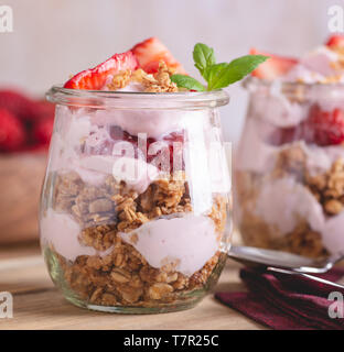 Nahaufnahme von einem Parfait mit Joghurt, Müsli und frischen Erdbeeren im Glas gemacht Stockfoto