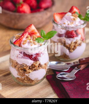 Nahaufnahme von einem Parfait mit Joghurt, Müsli und frischen Erdbeeren im Glas gemacht Stockfoto