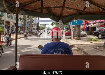 Der Blick von der Rückseite der Tuk Tuk, wie es schlängelt sich durch die belebten Straßen von Siem Reap, Kambodscha, der Fahrer trägt einen hellen roten Sturzhelm Stockfoto