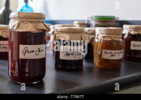 Eine Nahaufnahme von mehrere Gläser selbstgemachte Marmelade sitzen auf einer Arbeitsplatte, mit altmodischen braunen Papier und string Deckel mit handgeschriebenen Etiketten der ersten Jar im Fokus und den Rest unscharf Stockfoto