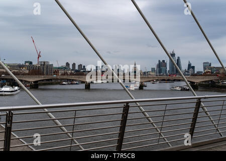 Ein Blick auf die Themse an einem bewölkten Tag von der Golden Jubilee Bridge, in der St. Paul's und die Skyline von London über das Geländer der Brücke suchen Stockfoto