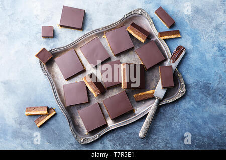 Schokolade Karamell Schichten, Bars, Millionäre shortbread auf einem vintage Fach blauen Hintergrund. Ansicht von oben. Stockfoto