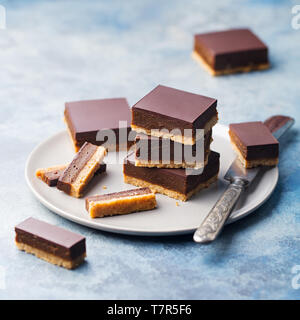 Schokolade Karamell Schichten, Bars, Millionäre shortbread auf einem grauen Platte. Blauen Hintergrund. Stockfoto