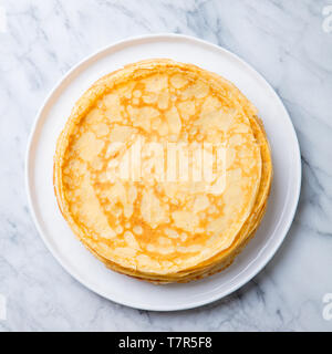 Crepes, dünne Pfannkuchen auf einer weißen Platte. Marmor Hintergrund. Cpace kopieren. Ansicht von oben. Stockfoto