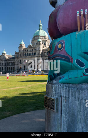 Victoria, Vancouver Island, BC, Kanada, 26. August, 2018: Blick auf die Parlamentsgebäude in Victoria, Vancouver Island, Kanada mit einem Totempfahl im Vordergrund und Touristen Fräsen um das Gebäude Stockfoto