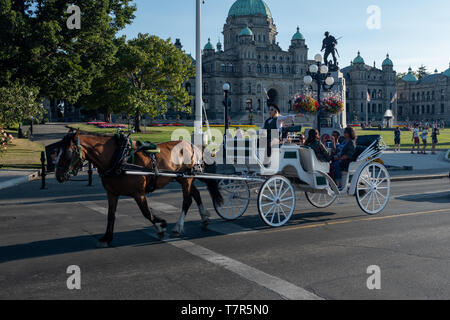 Victoria, Vancouver Island, BC, Kanada, 26. August, 2018: eine Kutsche mit Touristen an Bord geht das Parlament Gebäude in Victoria, Vancouver Island, Kanada Stockfoto