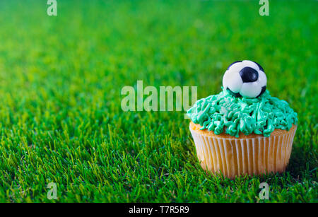 Cupcake mit Fußball-Ball auf grünem Gras Hintergrund eingerichtet. Kopieren Sie Platz. Stockfoto