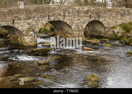 Eine Seitenansicht der Stein Pack Horse Brücke über den East Dart River in Dartmoor National Park, England mit niemandem über die Brücke Stockfoto