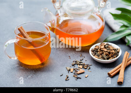 Kaffee mit Zimt in Glas Schale und Teekanne auf grauem Stein Hintergrund. Stockfoto