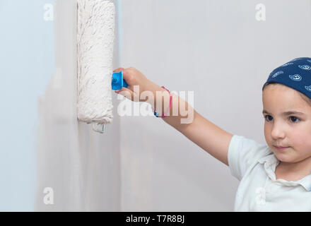 Kleines Mädchen mit farbroller in der Hand. Kinder helfen House Chores Konzept Stockfoto