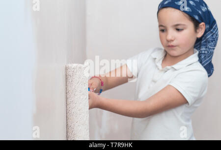 Kleines Mädchen mit farbroller in der Hand. Kinder helfen House Chores Konzept Stockfoto